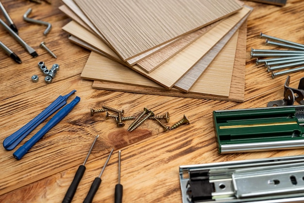 Dowels and screws with keys are scattered next to samples of wooden examples for home furniture The concept of furniture assembly