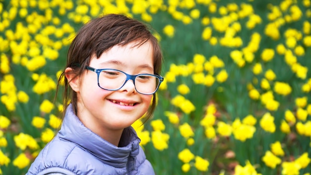 Down syndrome girl on background of flowers field