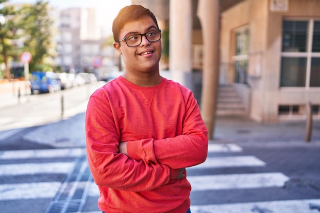 Down syndrome man smiling confident standing with arms crossed gesture at street