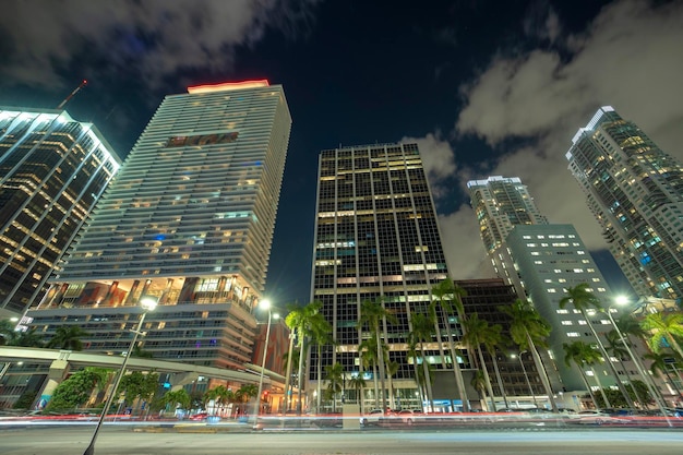 Downtown district of of Miami Brickell in Florida USA Brightly illuminated high skyscraper buildings and street with car trails and metrorail traffic in modern american midtown