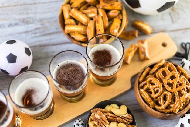 Draft beer and salty snacks on the table for soccer party.