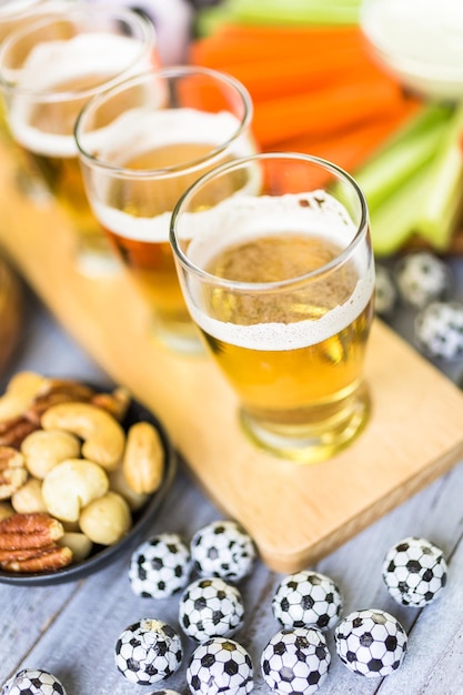 Draft beer and salty snacks on the table for soccer party.