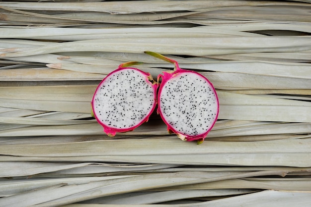 Dragon fruit slices, cut, half on palm leaves. Organic, still life photography concept.