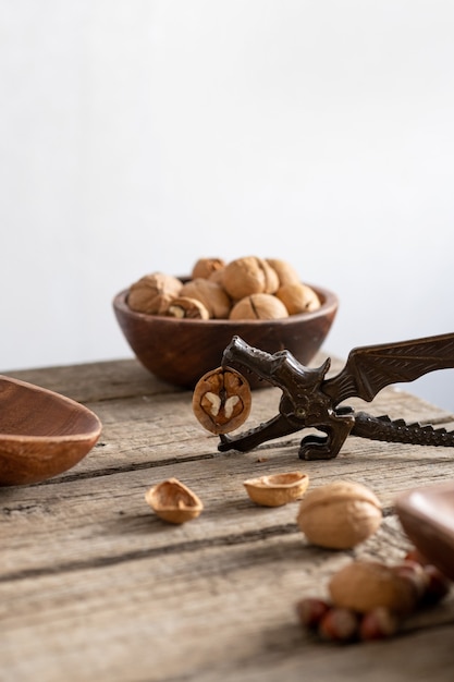 Dragon nutcracker is holding unshelled walnut on rustic wooden table. vertical