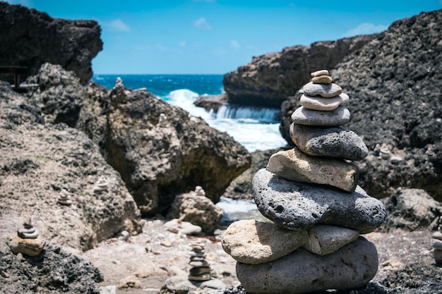 Dramatic handmade stone towers on a cliff in boka pistol curacao with blue sea panorama