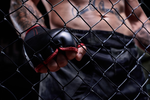 Dramatic image of a mixed martial arts fighter standing in an octagon cage Powerful abdominal muscles The concept of sports boxing martial arts