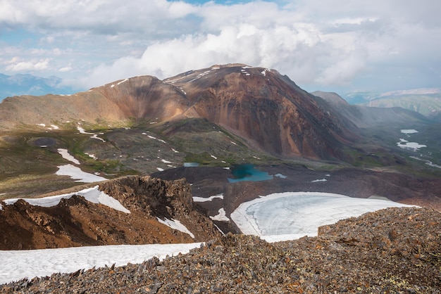 Dramatic landscape with contrast between sunny and rainy weather Awesome scenery with sharp rocks and small lake in mountain valley Changeable weather in mountains is sunny and cloudy at same time