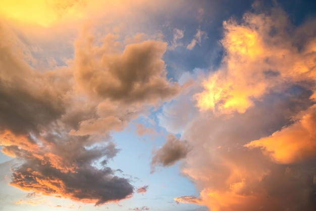 Dramatic moody sunset landscape with puffy clouds lit by yellow setting sun and blue sky