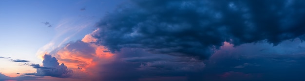 Dramatic panorama of sunset sky with dark stormy clouds.