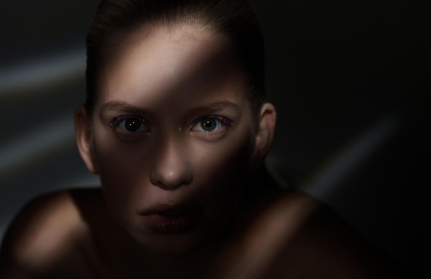 Dramatic portrait of woman with lights and shadows on her face.