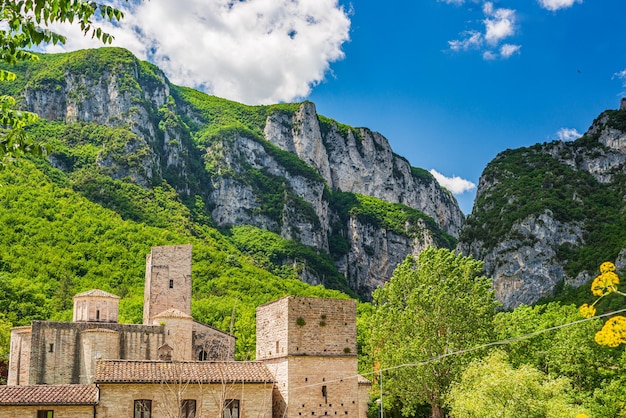 Dramatic sky over medieval village on river San Vittore Frasassi Marche Italy Romantic sky and clouds above mountains landscape tourism destination