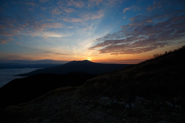 Dramatic sunset landscape in the autumn mountains over clouds Beautiful skyscape with sunny beams