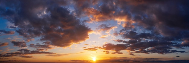 Dramatic sunset sky with clouds. Beautiful natural panorama of cloudy sky with setting sun.