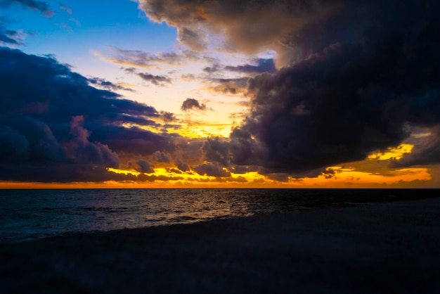 Dramatic sunset through a cloudy dark sky over waves at the sea.