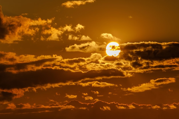 Dramatic sunset with clouds. The round sun sits down.