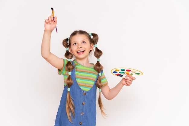 Drawing for children A little girl draws your advertisement with a brush on a white isolated background Courses for young artists in painting