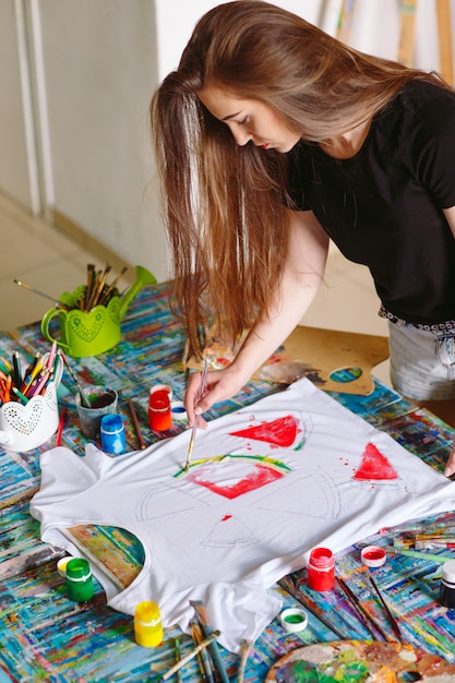 Drawing on clothes. Girl draws on a white T-shirt.