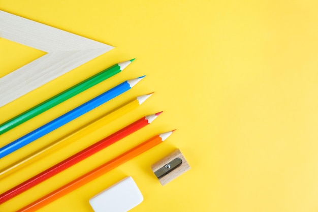 Drawing materials colored pencils an eraser sharpener and a ruler on a bright yellow background