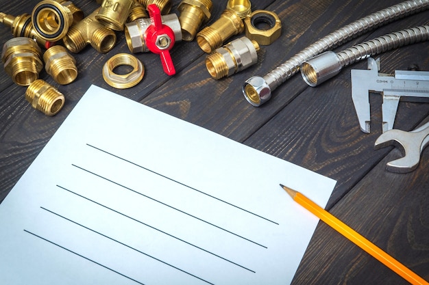 Drawing up plumbing repair plan with spare parts and hoses on black boards