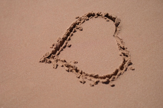 Drawn heart on wet sand on beach