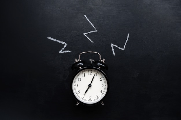 Drawn sounds alarm clock with a dial shows the time  and rings on a slate background