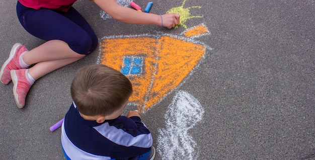 Draws a rainbow sun car with chalk on the asphalt