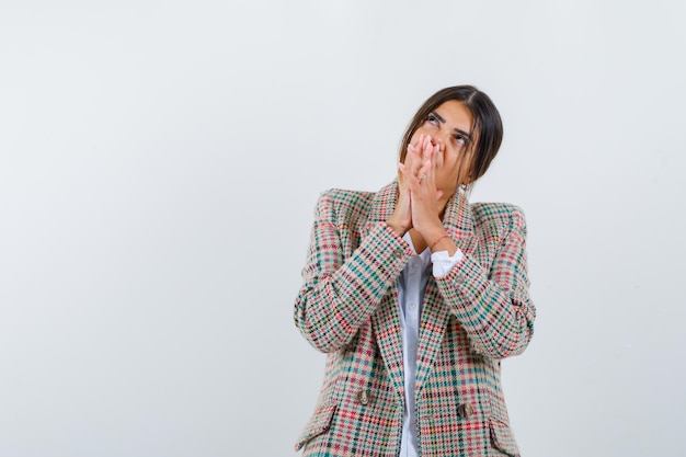 Dreamer mexican woman in white shirt and check jacket hands clasped and dreaming isolated on white background