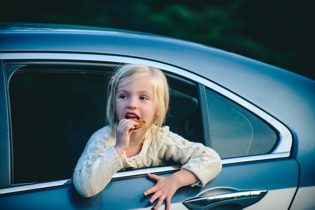 Dreaming child girl look out from the car window Portrait of little child girl sitting in car Cute little child girl smiling and having fun to travel by car