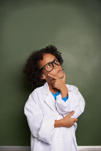 Dreaming of his bright future An ethnic boy wearing glasses and a lab coat looking contemplative copyspace