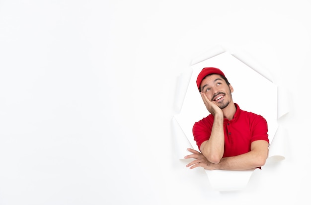 Dreaming young courier in red uniform on white