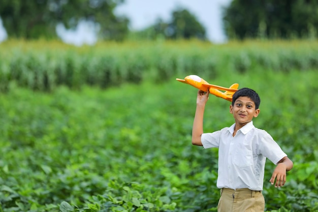 Dreams of flight! indian child playing with toy airplane at green field