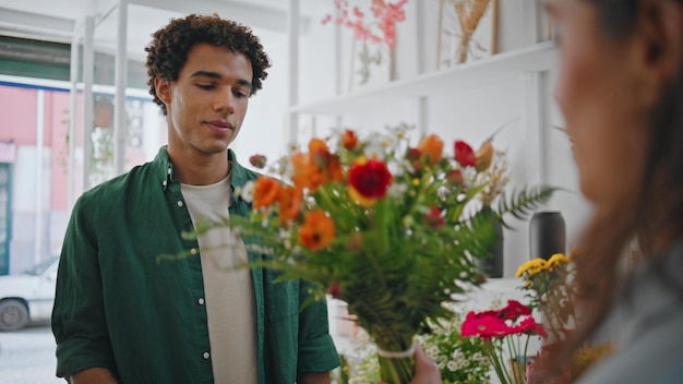 Dreamy african man smell flowers composition young man enjoy floral bouquet