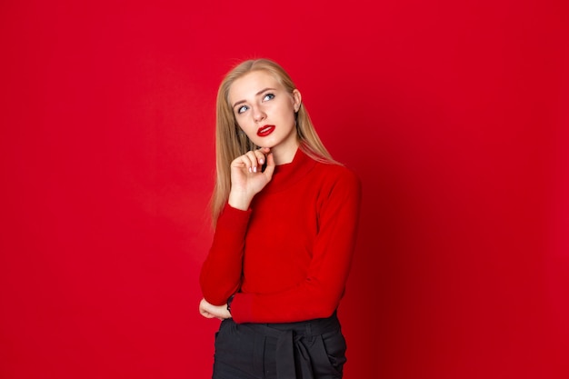 Dreamy beautiful blonde woman standing on a red background 