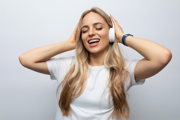 Dreamy girl in headphones listening to music on a white background