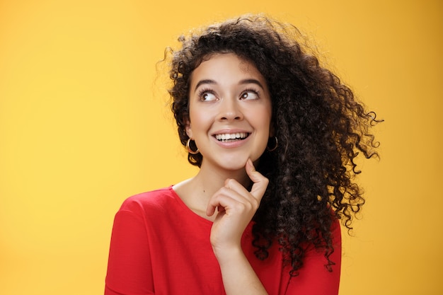 Dreamy girl making assumptions what gets as christmas present looking curious and happy at upper lef...