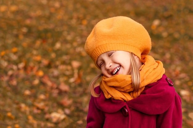 Dreamy little girl in a yellow beret and autumn clothes on an autumn background