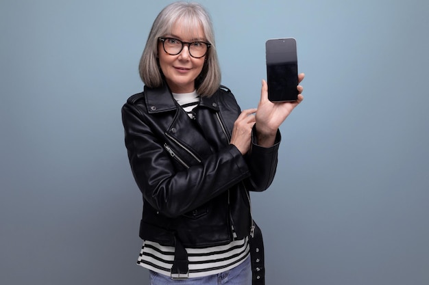 Dreamy modern s modern old lady with gray hair holding a device vertically with a mockup on a bright