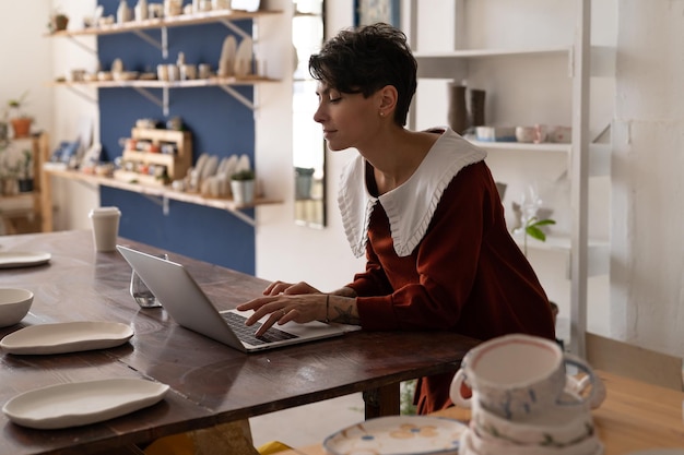 Dreamy relaxed young woman working at laptop checking orders at her online shop rest after work