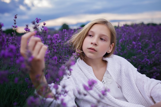 Dreamy teenager girl walks among purple flowers on beautiful sunset summer travel vacation