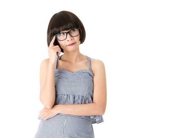 Dreamy young Asian female in casual checkered dress and trendy eyeglasses looking up pensively isolated on white background