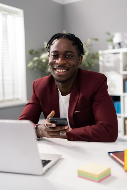 Dressed in maroon jacket man sits at white desk in bright spacious office gray