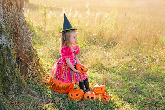 Dressedup child is sitting on large painted sinister pumpkin