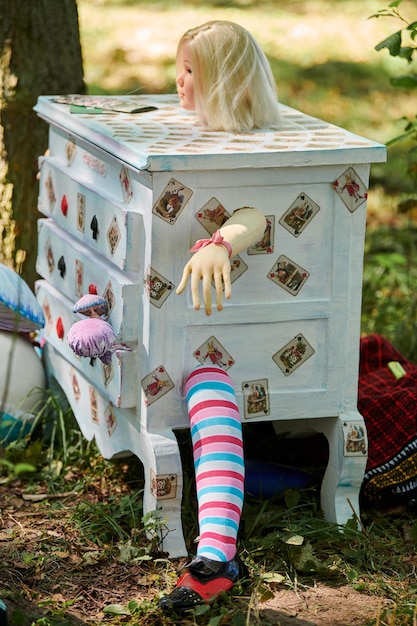 Dresser with doll Alice inside near Humpty Dumpty and mushrooms art object on outdoor art exhibition