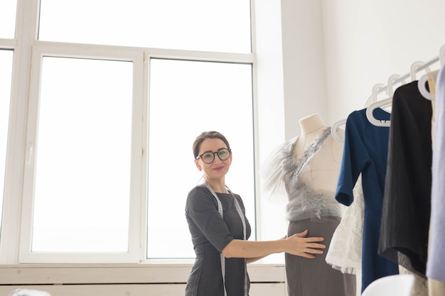 Dressmaker, tailor, fashion and showroom concept - Portrait of talented female dressmaker working with textile for sewing clothes.