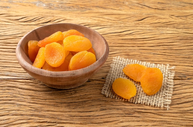 Dried apricots in a bowl over wooden table