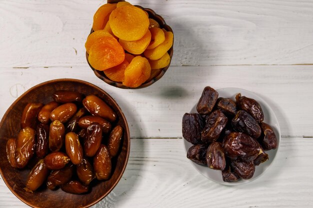 Dried apricots and dates fruit on white wooden table Top view