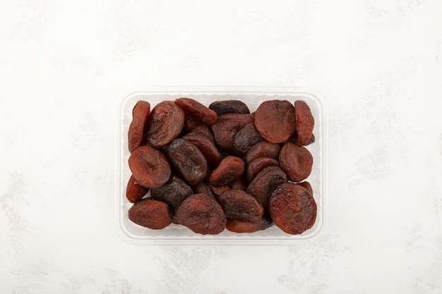 Dried apricots in plastic container top view Dehydrated sweet apricot fruits Alternative healthy sweets