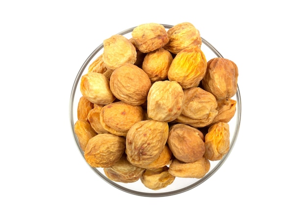 Dried apricots with pits uryuk in a bowl isolated on white background