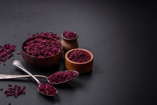 Dried beets in small slices in a wooden bowl on a black concrete background