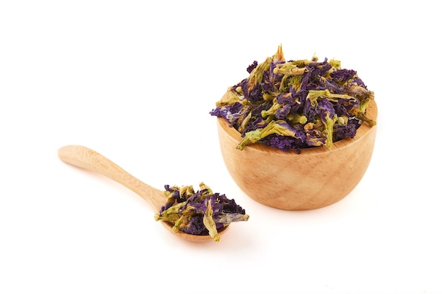 Dried butterfly pea flowers Asian pigeonwings Clitoria ternatea placed in a wooden bowl and spoon isolated on white background